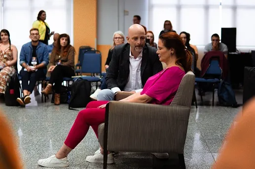 Marcelo Behn em prática com uma participante sentada, diante da turma
